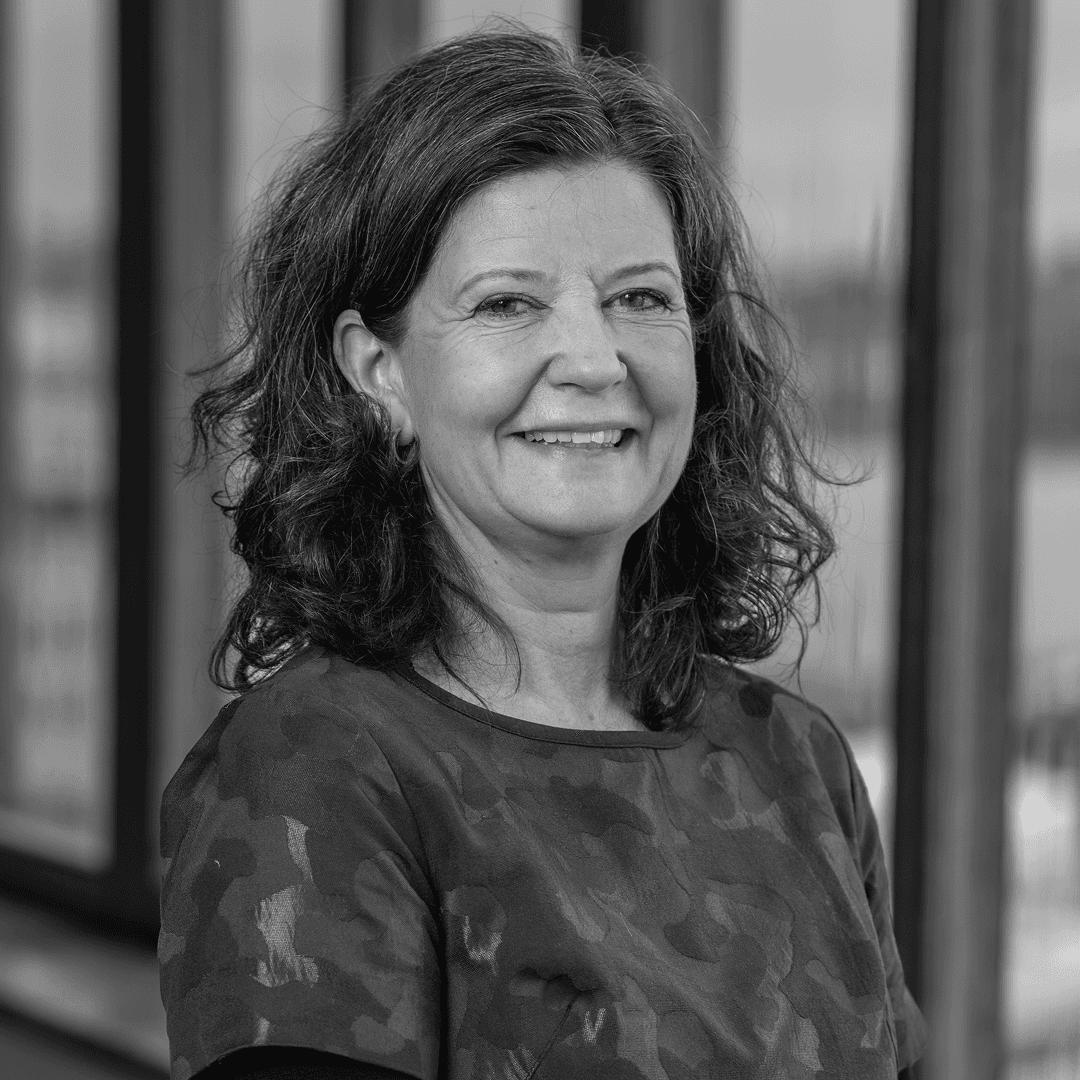 Kvinna med axellångt hår, ler mot kameran för porträtt-bild.