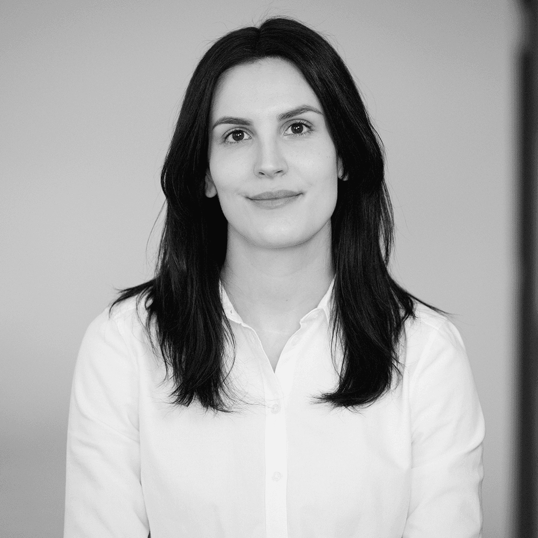 Kvinna med vit skjorta och axel-långt mörkt hår.