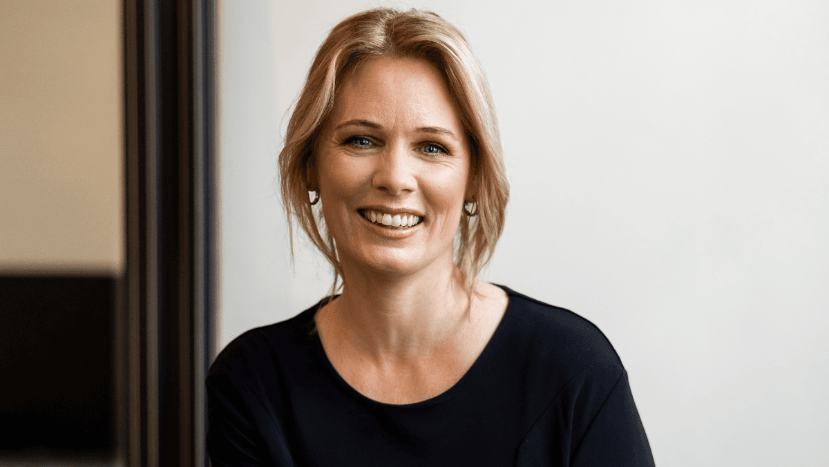 Blond kvinna med toffs, ler och tittar in i kameran.