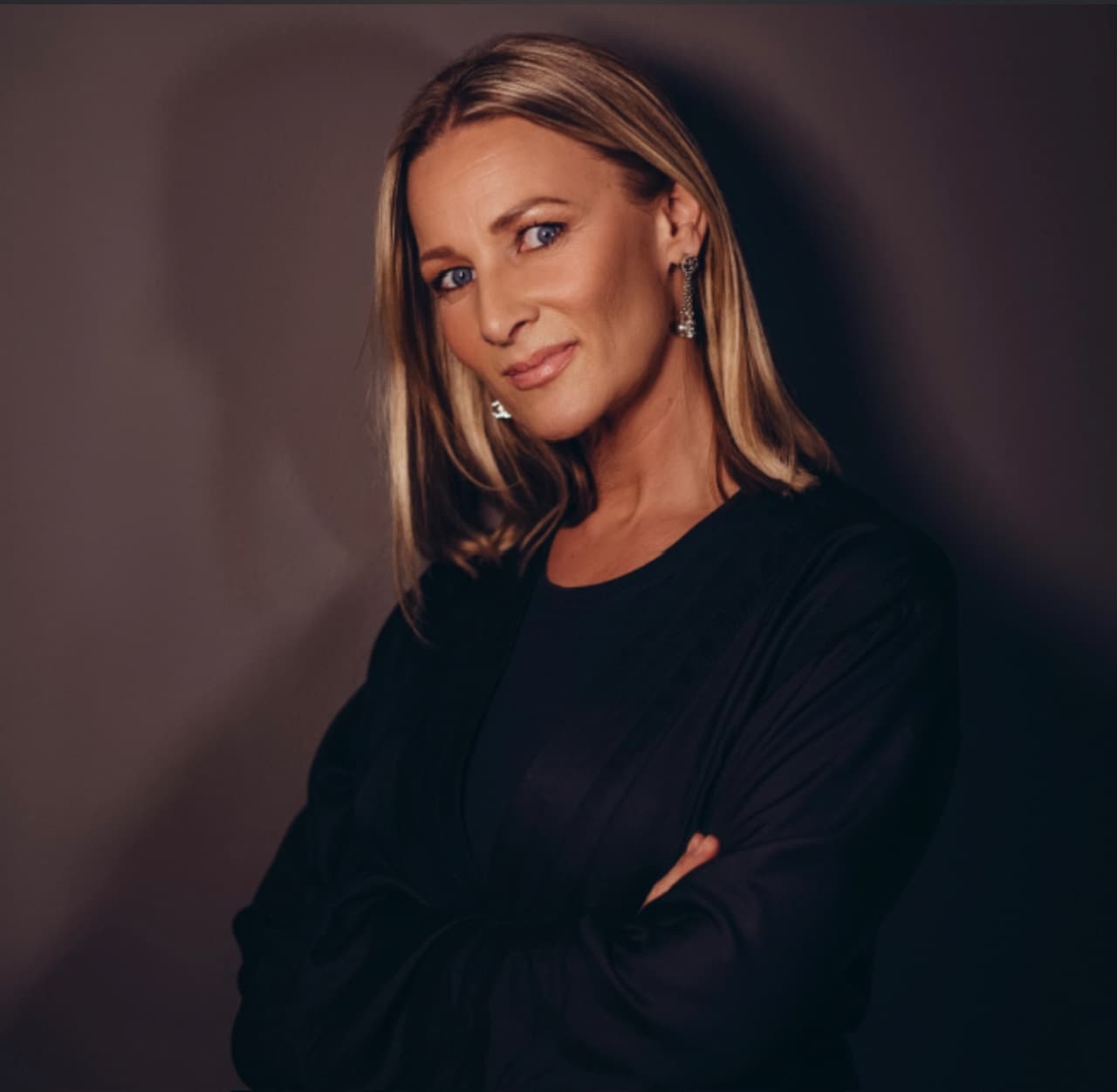 Blond kvinna med svart tröja poserar för kameran i porträttbild.