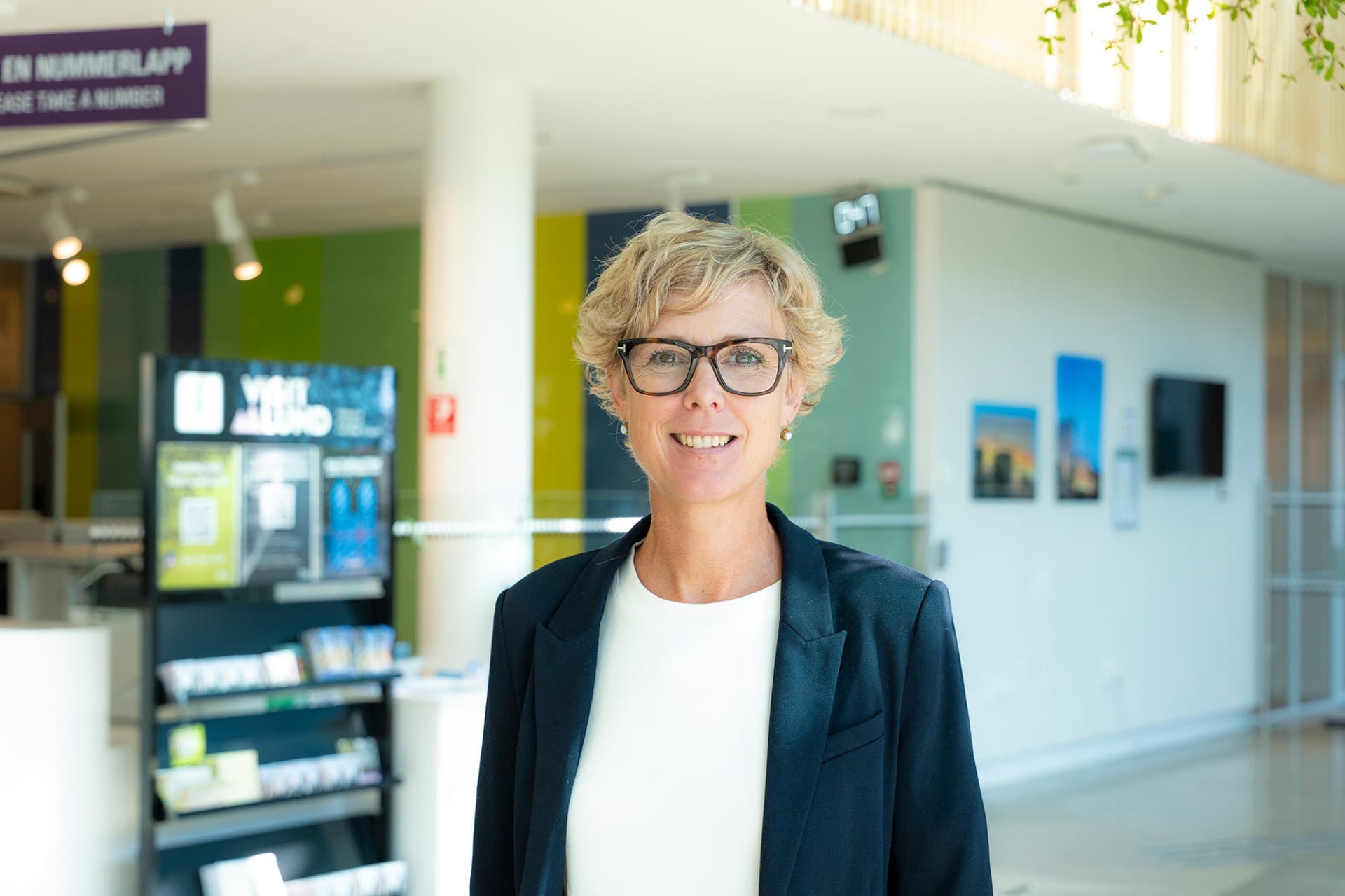 Blond, kortklippt kvinna med svarta glasögon.
