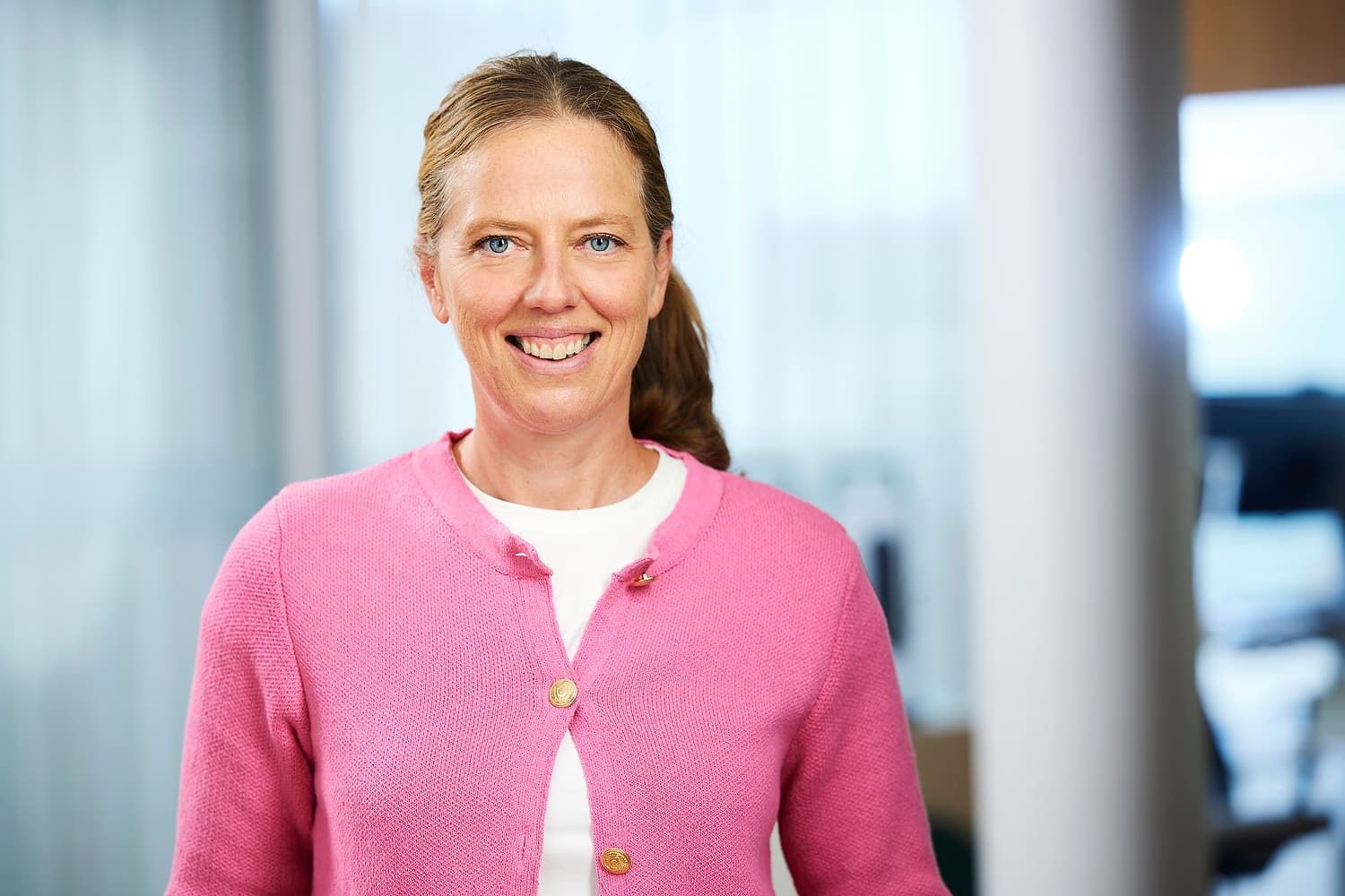Kvinna i rosa tröja och toffs. Let mot kameran