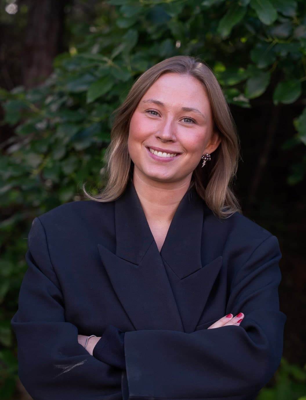 Ljushårig svartklädd kvinna ler in i kameran