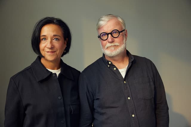 Kvinna med mörk page och man med grått hår och svarta glasögon.