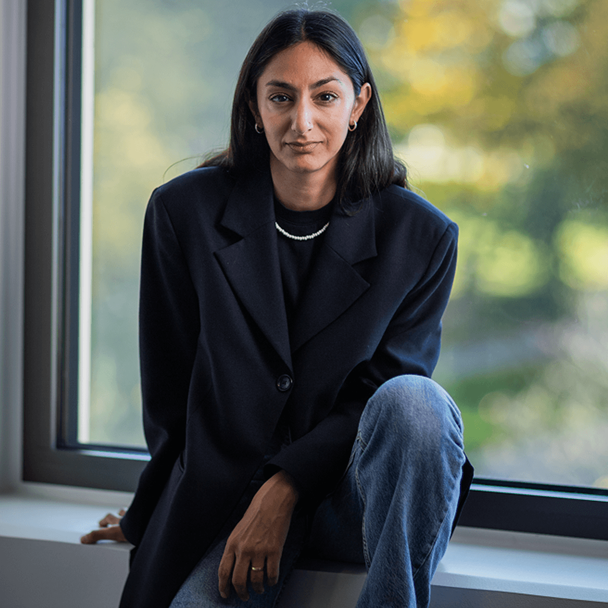 Kvinna sitter i ett fönster, klädd i svart kavaj.