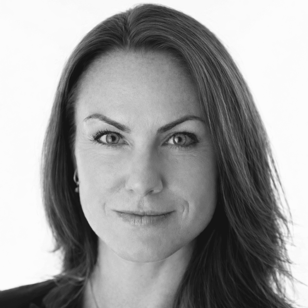 Kvinna med brunt hår, ler och tittar in mot kameran.