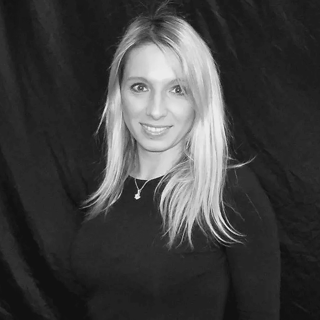 Blond kvinna med axellångt hår, svarta kläder ler mot kameran,