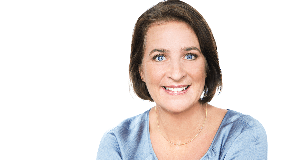 Kvinna med kortklippt brunt hår, ler och tittar in mot kameran med blåa ögon.