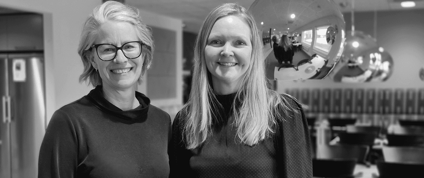 Två kvinnor ler och tittar in mot kameran.