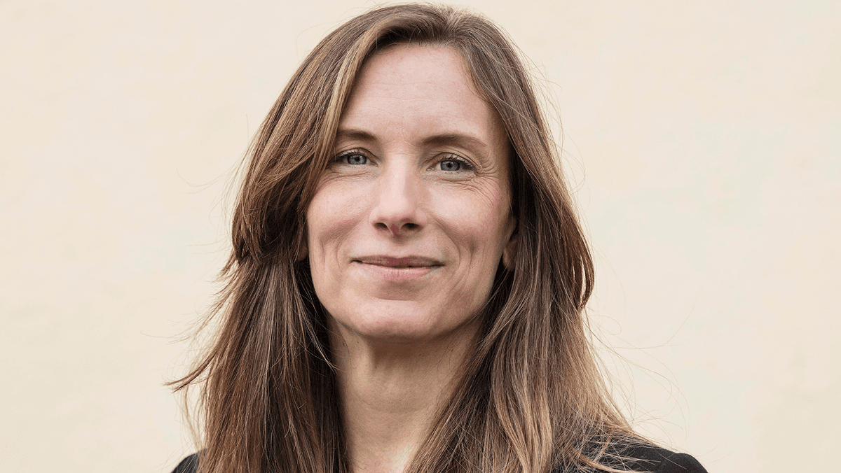 Kvinna med brunt axellångt hår, ler mot kameran.