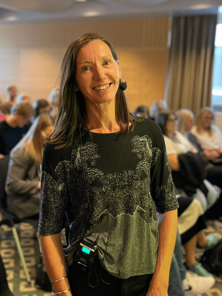 Kvinna i en föreläsningsmiljö, redo att gå på scen.