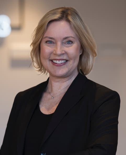 Blond kvinna i helsvart, ler mot kameran.