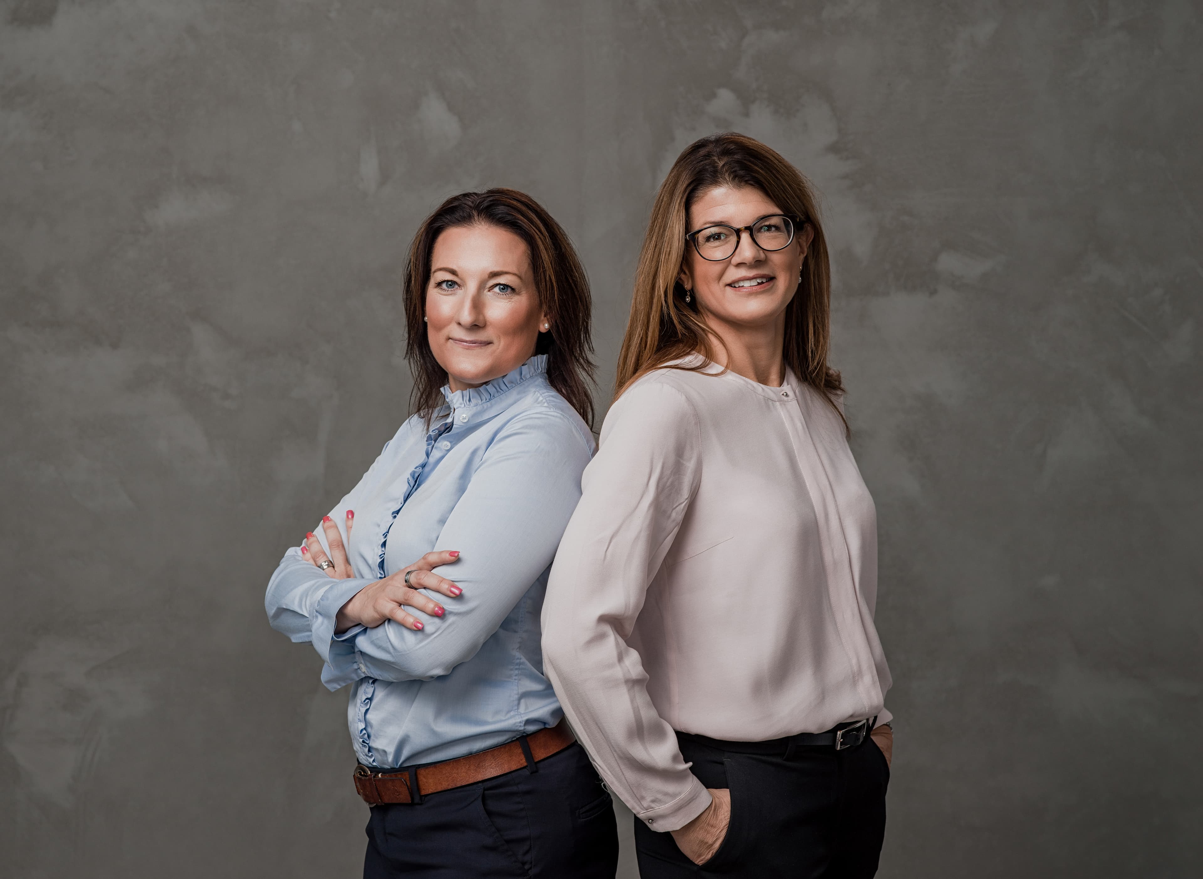 Två kvinnor står rygg mot rygg för foto.