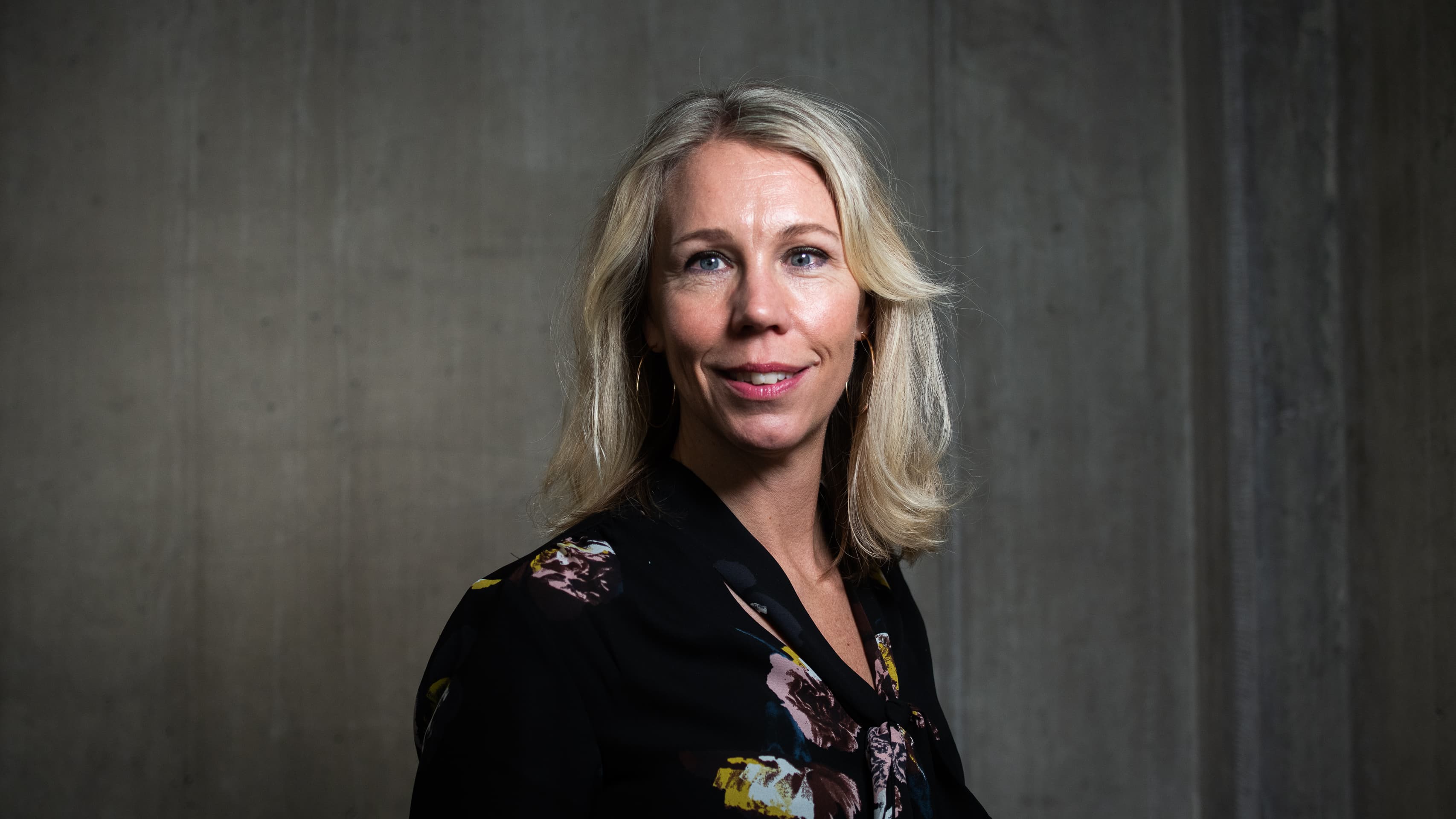 Porträttbild på en blond kvinna med svart klädsel.